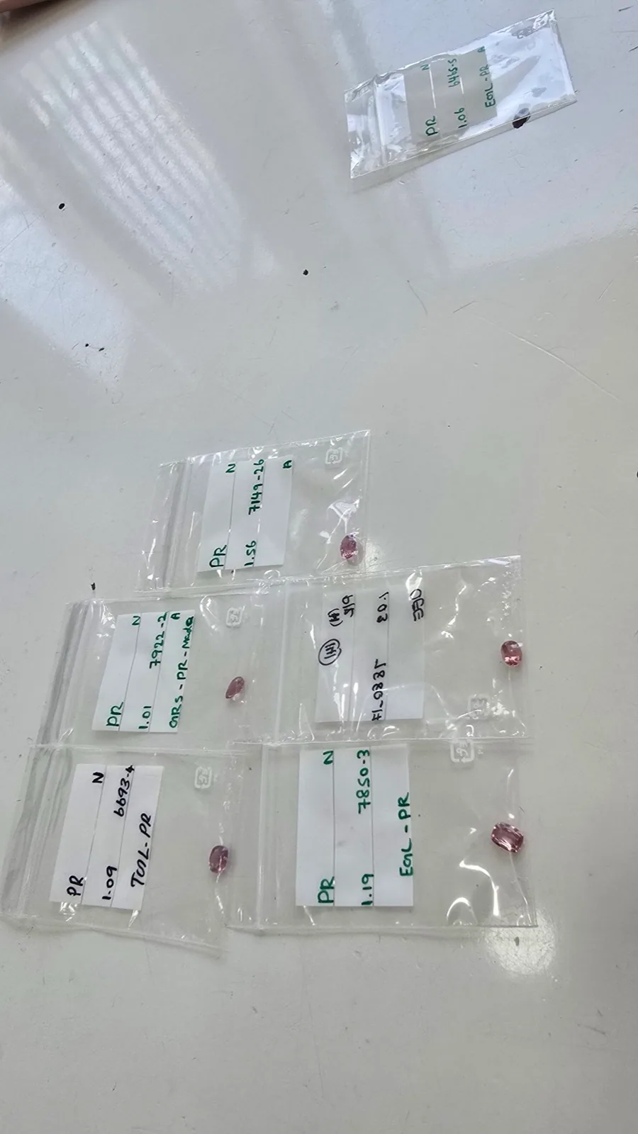 Labeled pink sapphire parcels in baggies with handwritten lab references and weights